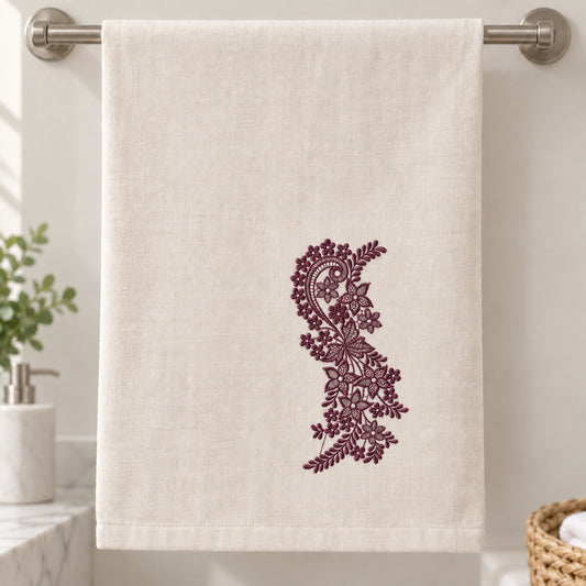 Linen hand towel with a dark aubergine floral paisley vine near the lower right, showing blossoms and fern-like leaves.