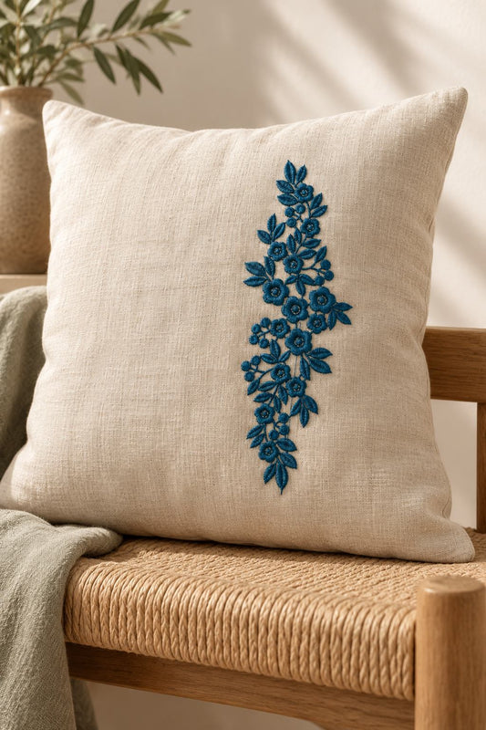 Photorealistic vertical rose leaf spray machine embroidery in deep forest teal thread on a linen cushion, shown as one fabric-stitched motif