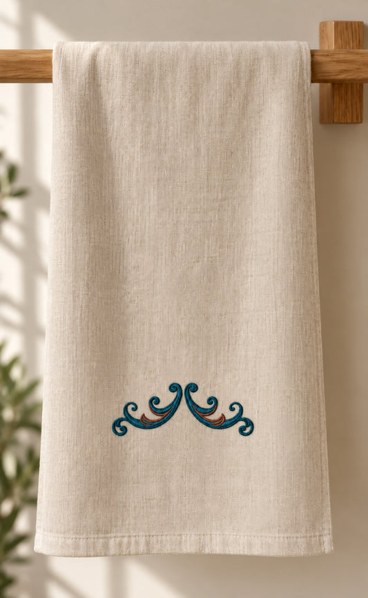 Twin Curl Acanthus Swag embroidered in petrol teal and muted copper on a linen guest towel, showing the complete two-color motif.