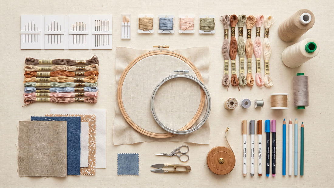 Essential hand and machine embroidery tools arranged on a textile worktable