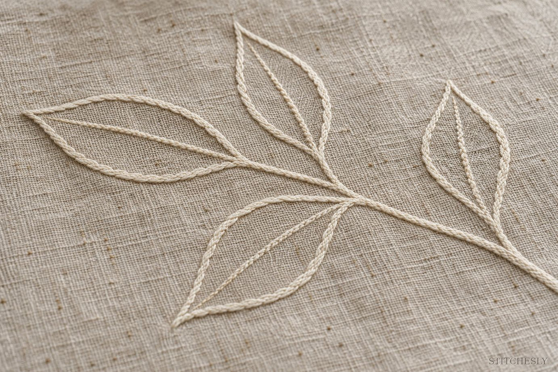 Ivory stitched leaf outlines with open unstitched centres on natural linen
