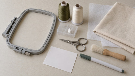 A compact embroidery project kit with hoop, thread, bobbin, scissors, brush, marker, fabric and backing.