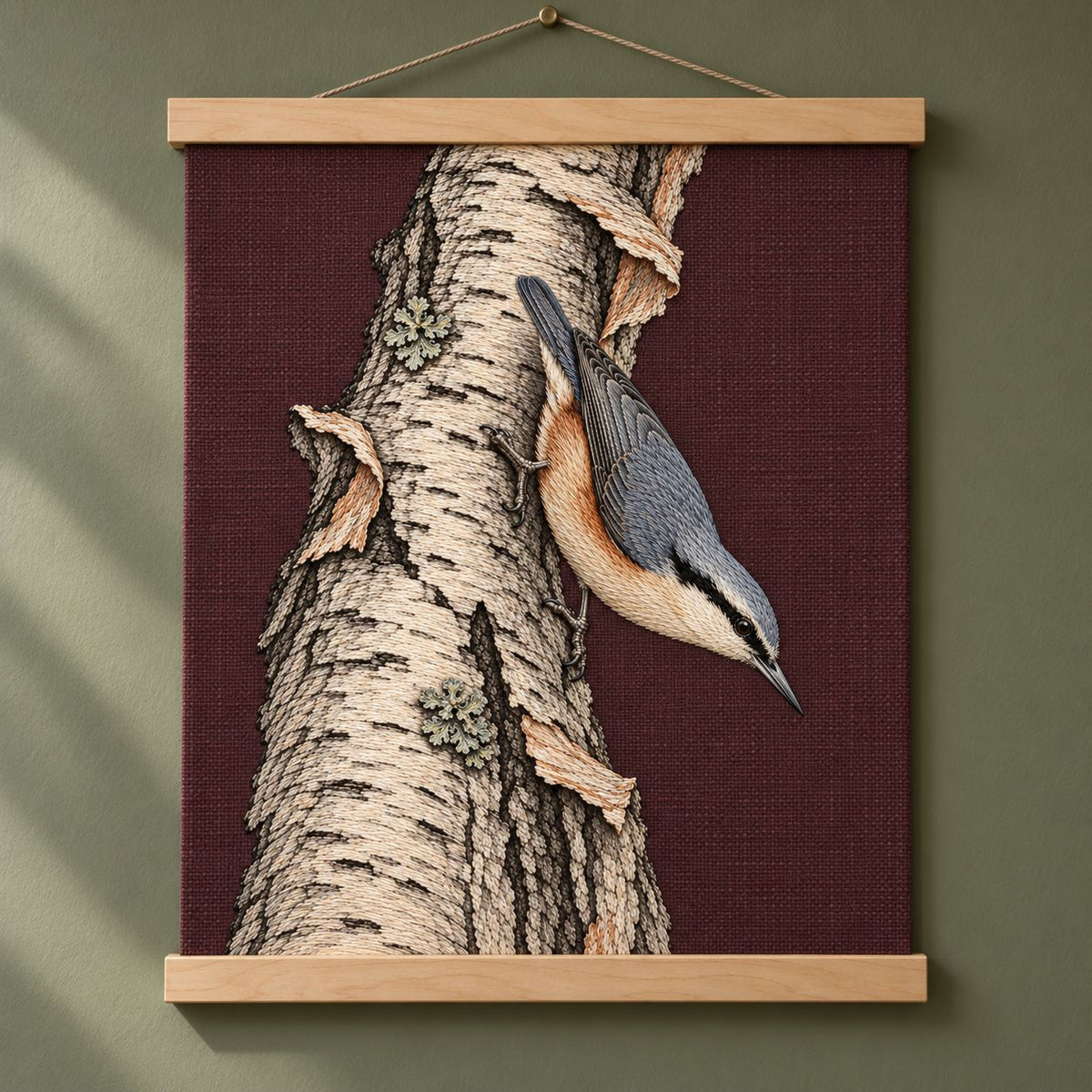 Nuthatch Descending the Silver Bark visual mockup shown as a hanging textile held by wooden rails, with the design on muted burgundy linen.