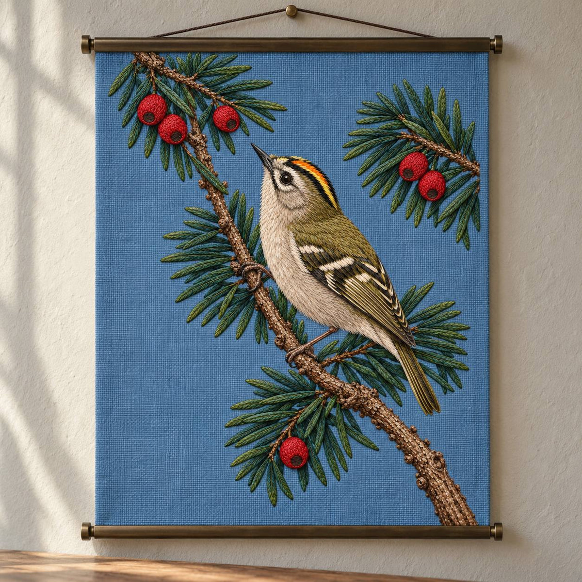 Goldcrest in the Yew Shadow visual mockup shown as a hanging textile held by wooden rails, with the design on muted blue linen.