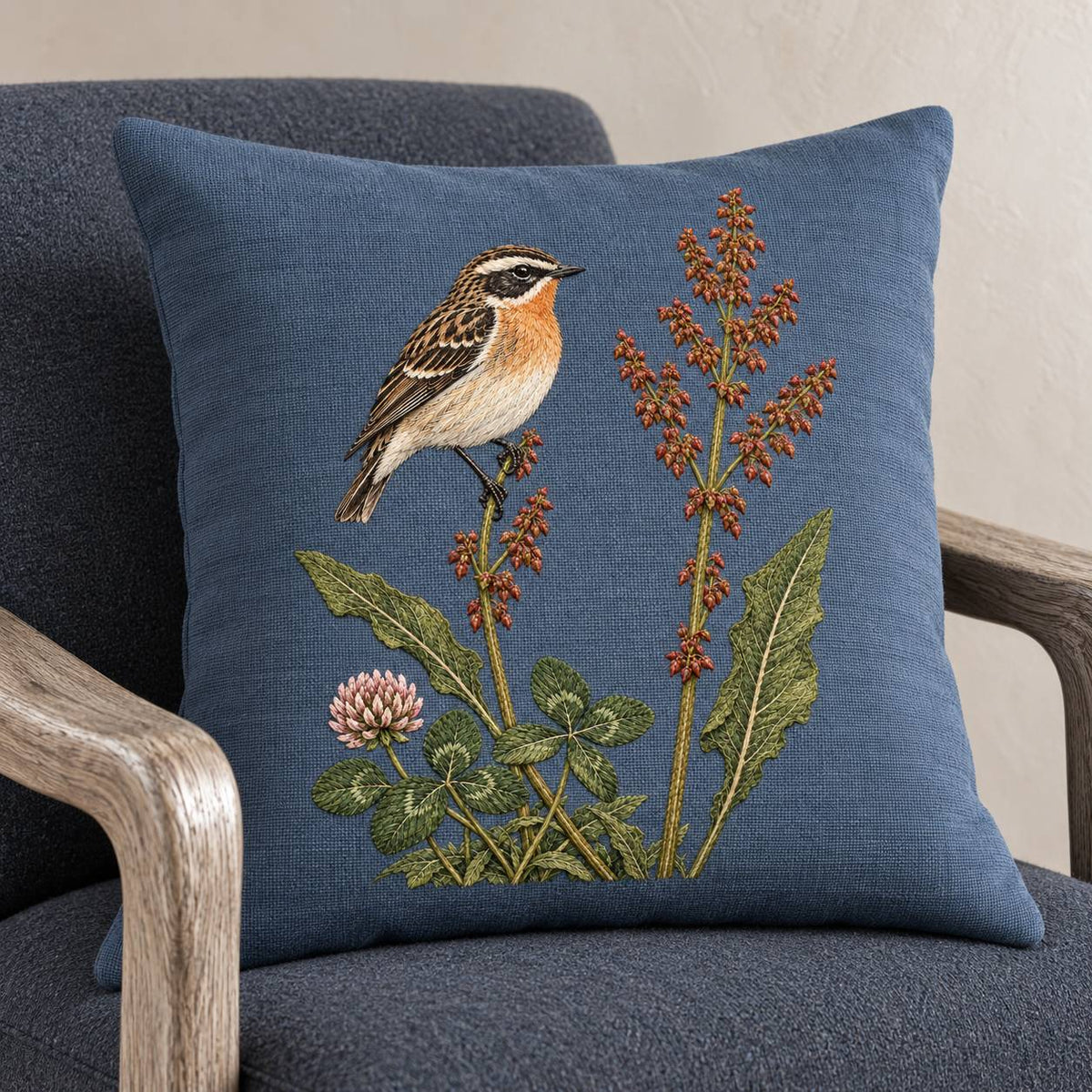 Whinchat Between the Sorrel Spears visual mockup shown on a cushion in a lounge chair, with the design on muted slate-blue linen.