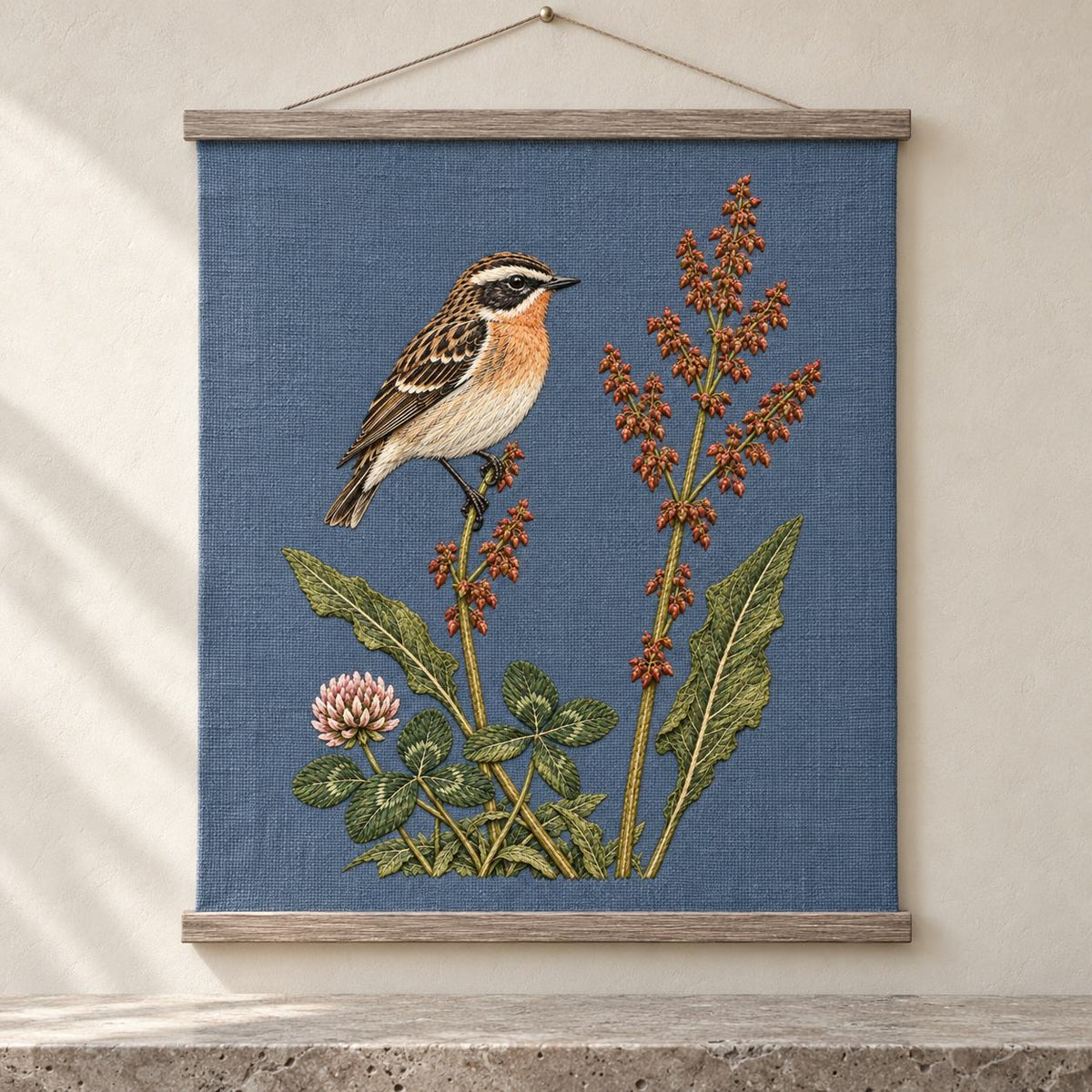 Whinchat Between the Sorrel Spears visual mockup shown as a hanging textile held by wooden rails, with the design on muted slate-blue linen.