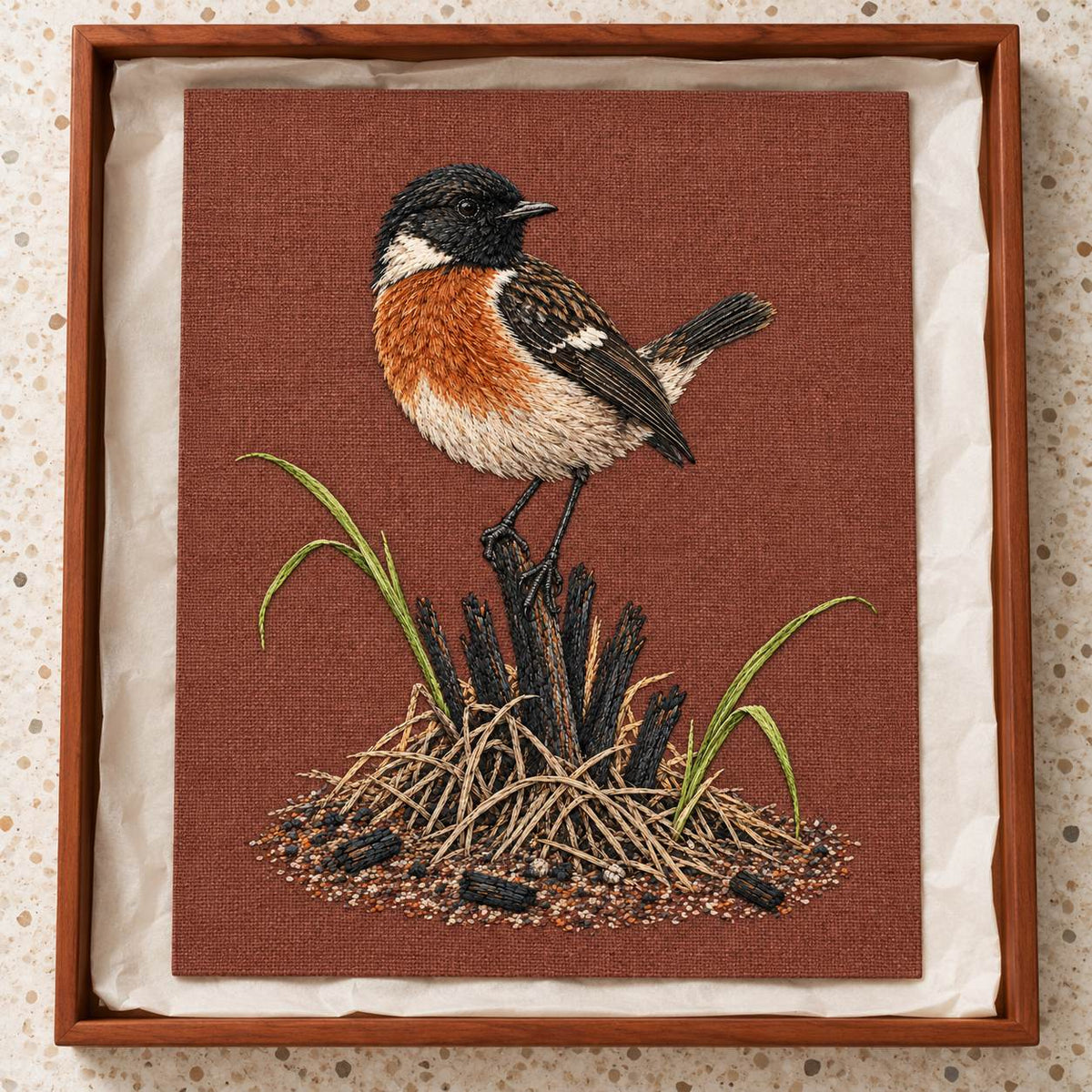 Stonechat at the Charred Grass Knot visual mockup shown as a textile panel in a collection tray, with the design on terracotta linen.