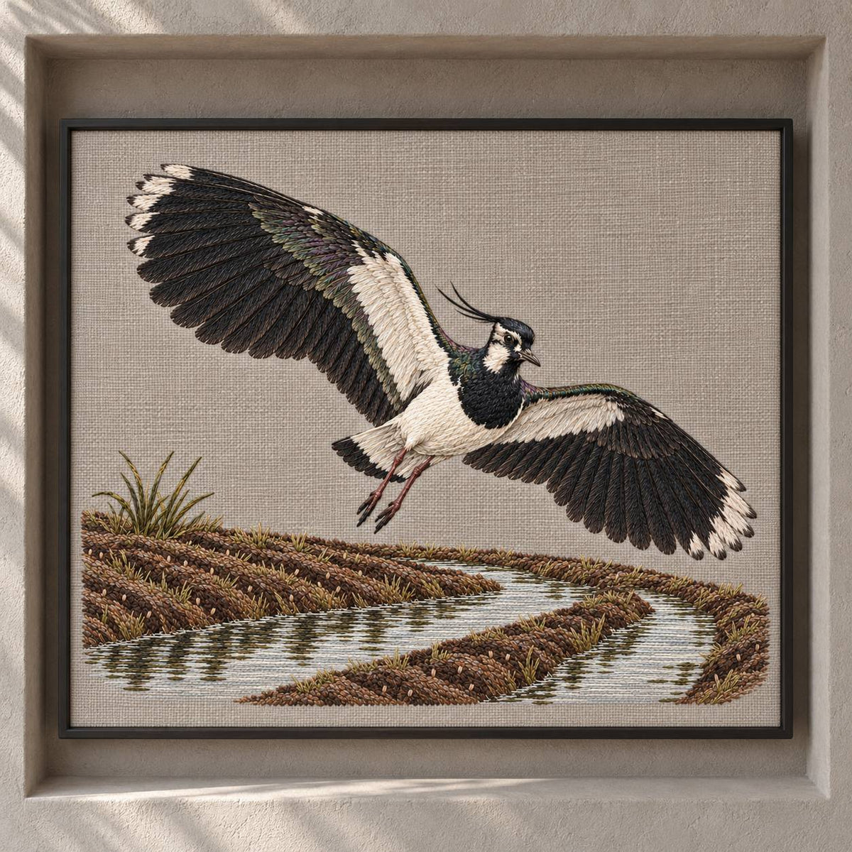 Lapwing Over the Wet Furrow visual mockup shown as a framed textile in a gallery niche, with the design on warm grey linen.