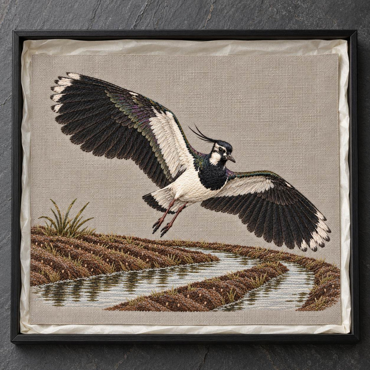 Lapwing Over the Wet Furrow visual mockup shown as a textile panel in a collection tray, with the design on warm grey linen.