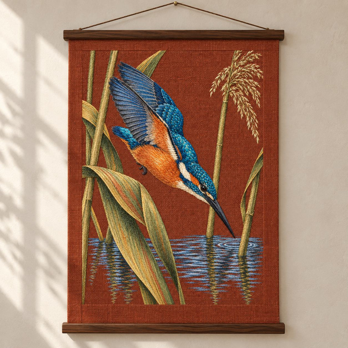 Kingfisher Through the Reed Window visual mockup shown as a hanging textile held by wooden rails, with the design on terracotta linen.