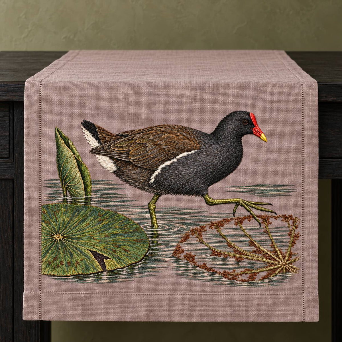Moorhen Along the Lily Rib Passage visual mockup shown on a textile runner over a console, with the design on warm mushroom linen.
