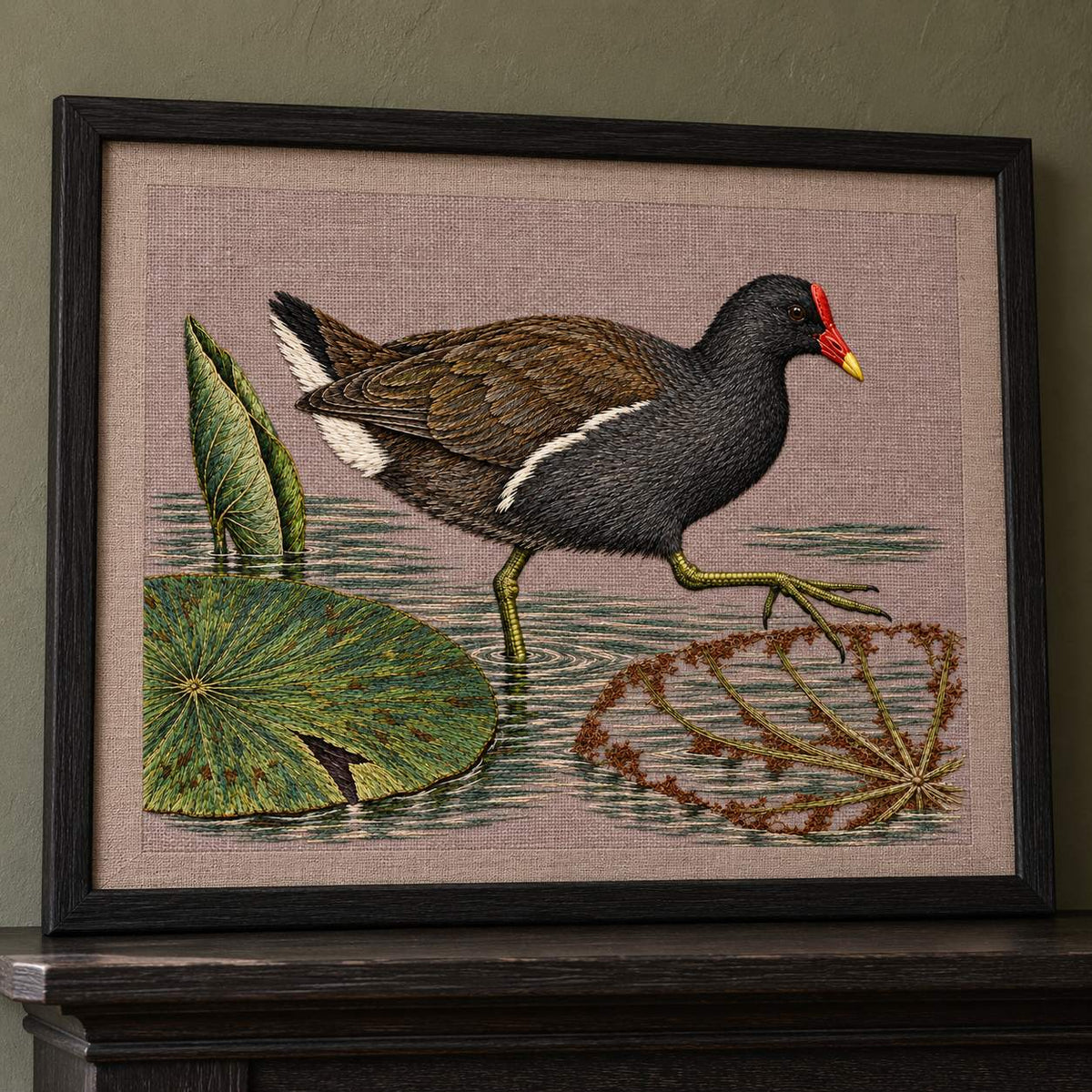 Moorhen Along the Lily Rib Passage visual mockup shown in a frame leaning on a mantel, with the design on warm mushroom linen.