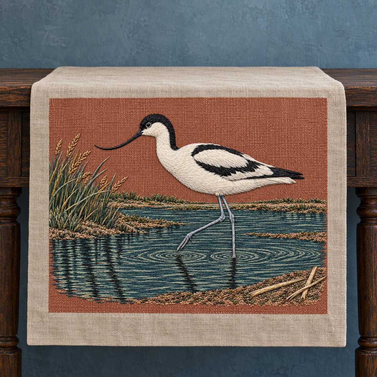 Avocet Across the Blackwater Line visual mockup shown on a textile runner over a console, with the design on dusty terracotta linen.