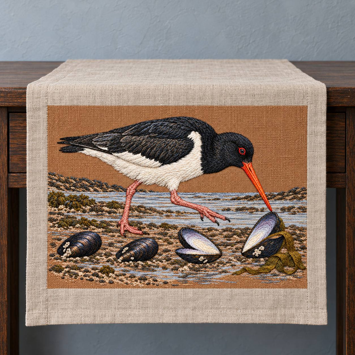 Oystercatcher Across the Mussel Line visual mockup shown on a textile runner over a console, with the design on warm ochre linen.