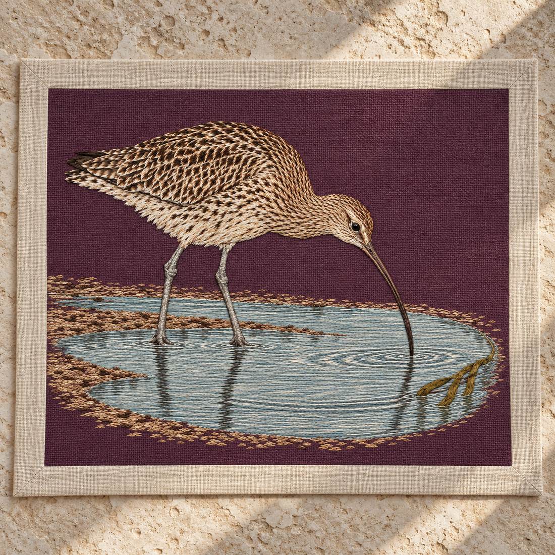 Curlew Under the Long Tide Moon visual mockup shown as a textile panel on a stone platform, with the design on deep plum linen.