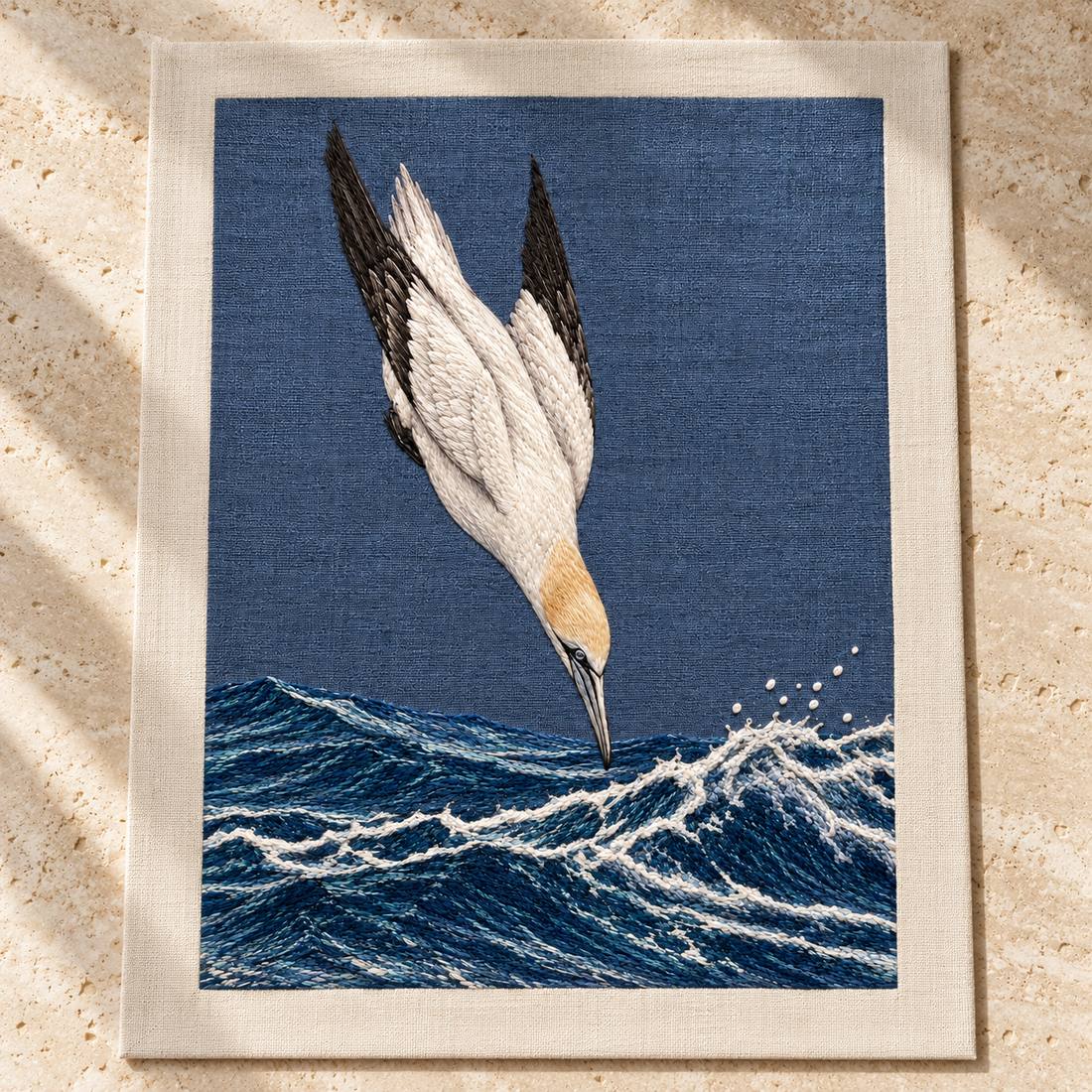Gannet in the Whitewater Plunge visual mockup shown as a textile panel on a stone platform, with the design on slate-blue linen.