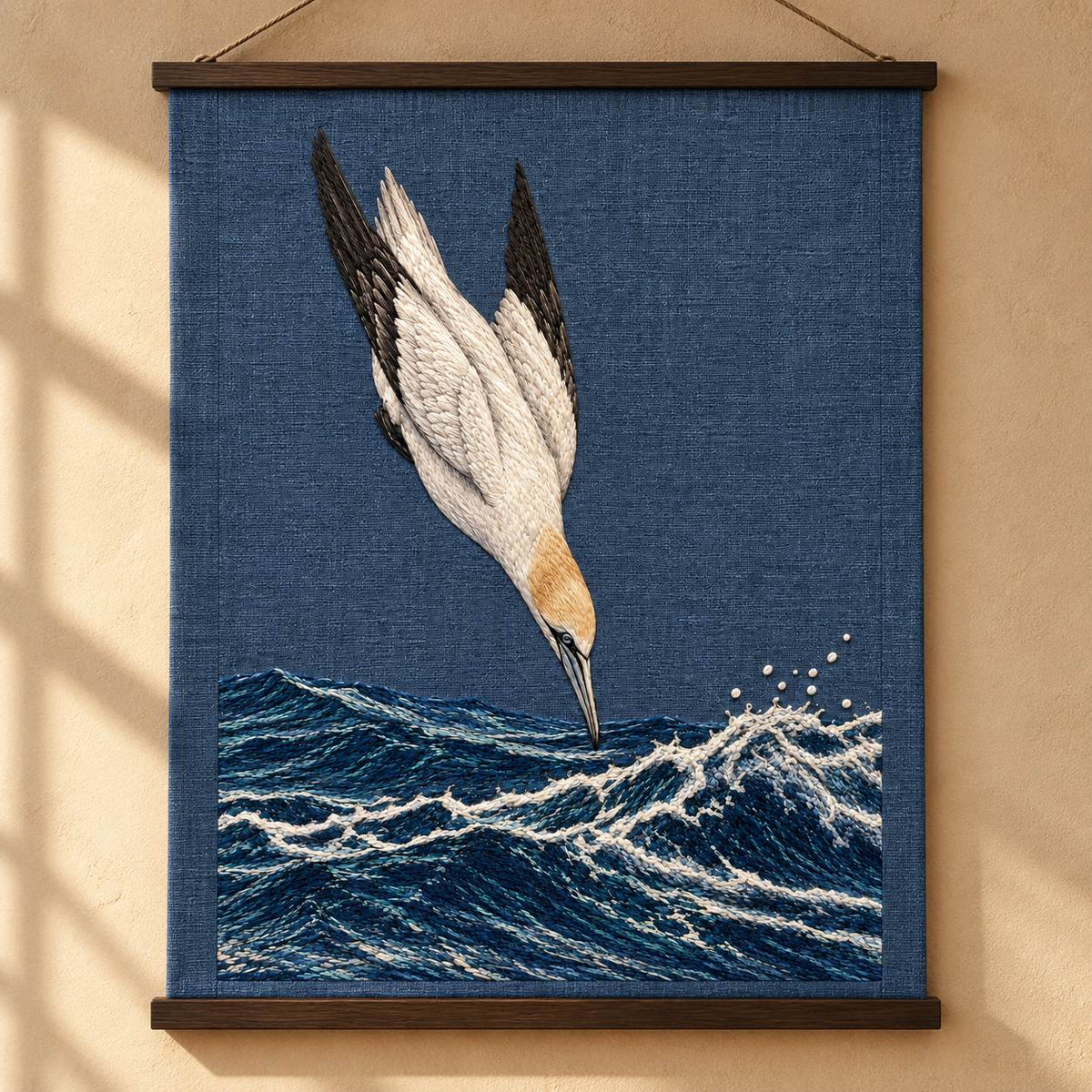 Gannet in the Whitewater Plunge visual mockup shown as a hanging textile held by wooden rails, with the design on slate-blue linen.