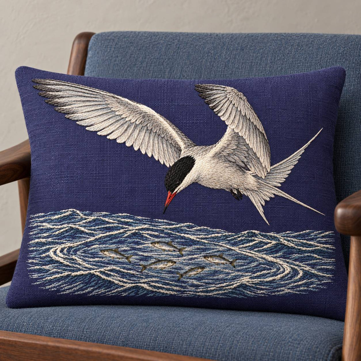 Common Tern Above the Silver Shoal visual mockup shown on a cushion in a lounge chair, with the design on deep blue-violet linen.