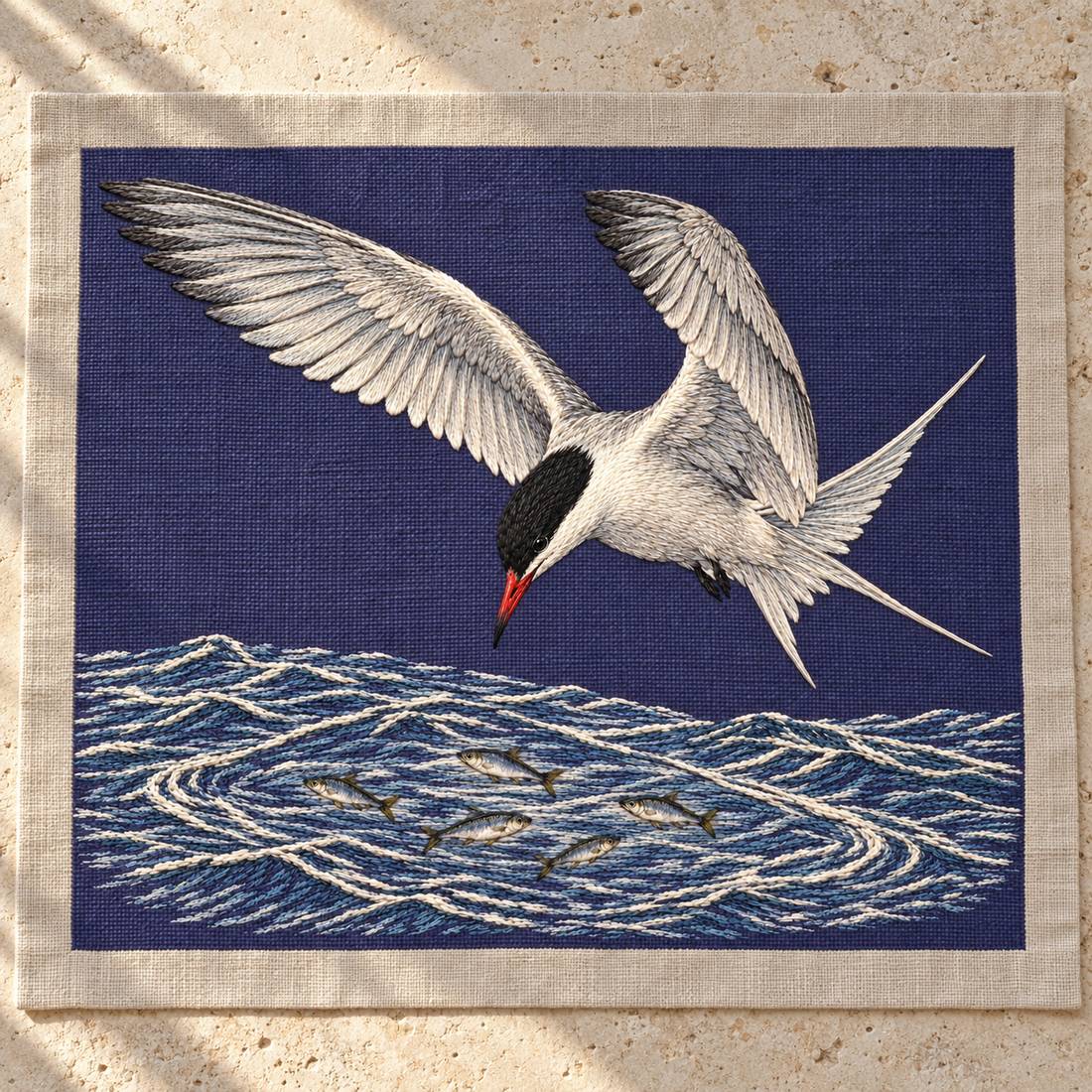 Common Tern Above the Silver Shoal visual mockup shown as a textile panel on a stone platform, with the design on deep blue-violet linen.