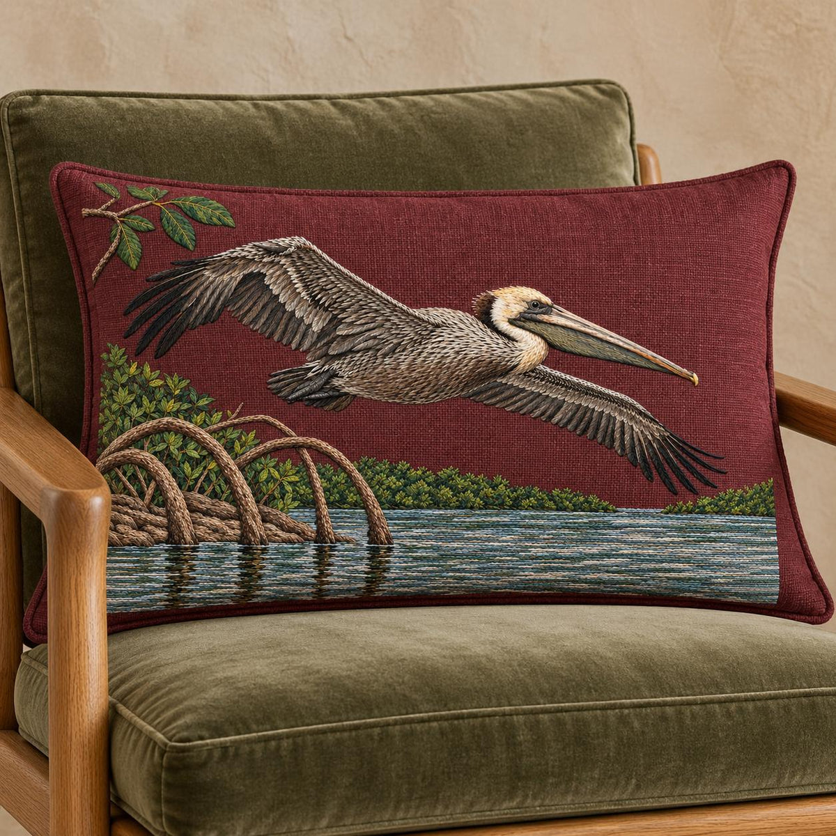 Pelican Over the Mangrove Mirror visual mockup shown on a cushion in a lounge chair, with the design on deep burgundy linen.