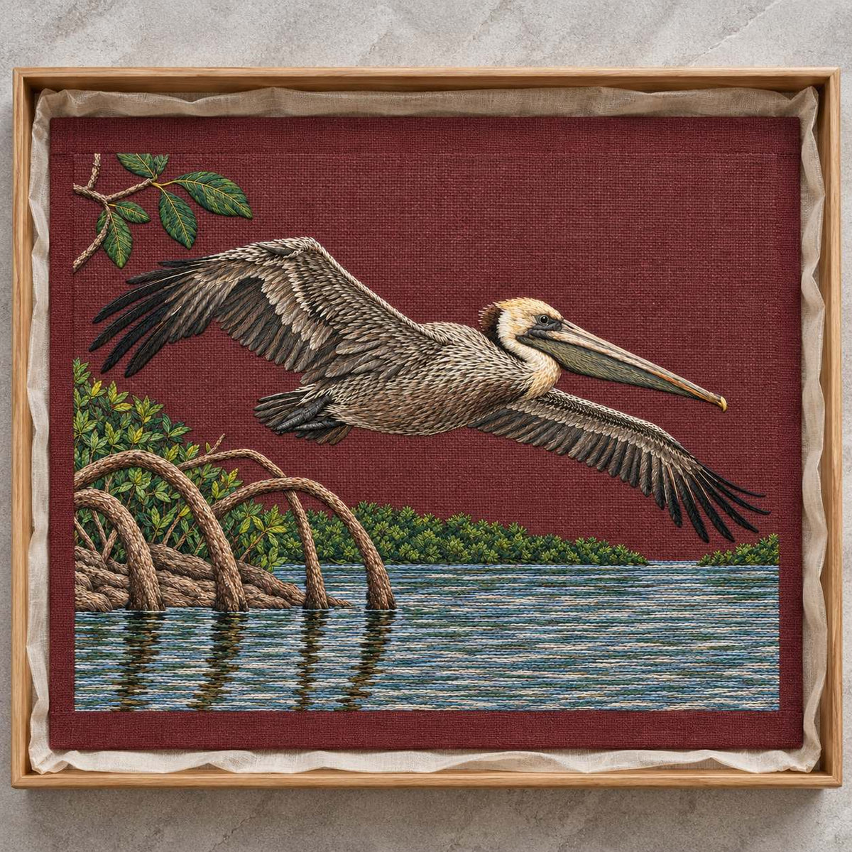 Pelican Over the Mangrove Mirror visual mockup shown as a textile panel in a collection tray, with the design on deep burgundy linen.