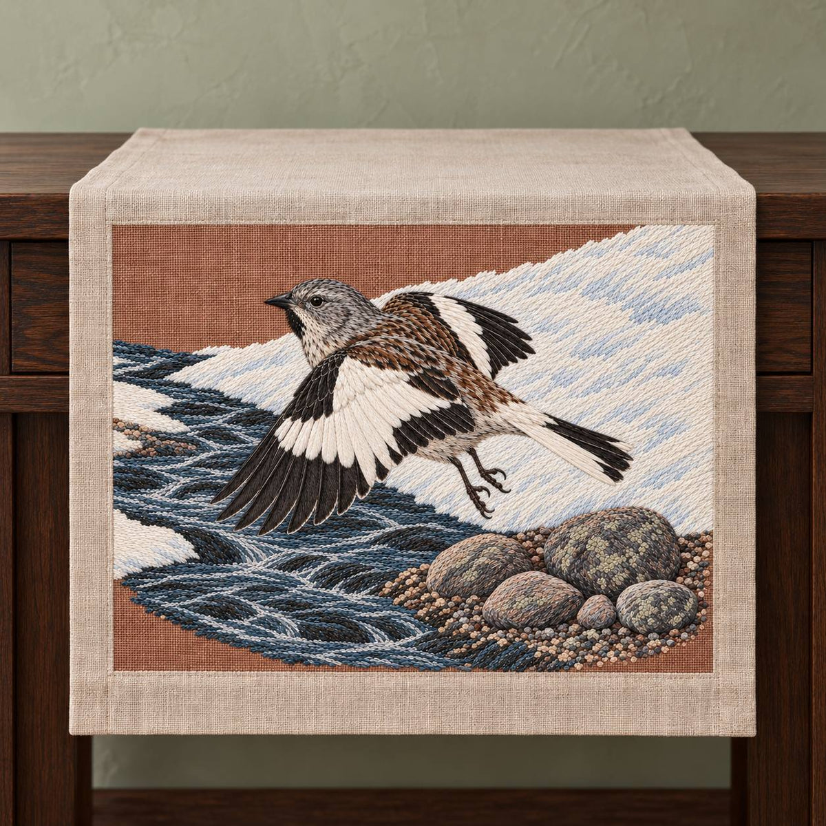 Snowfinch Along the Meltwater Cut visual mockup shown on a textile runner over a console, with the design on warm oatmeal linen.
