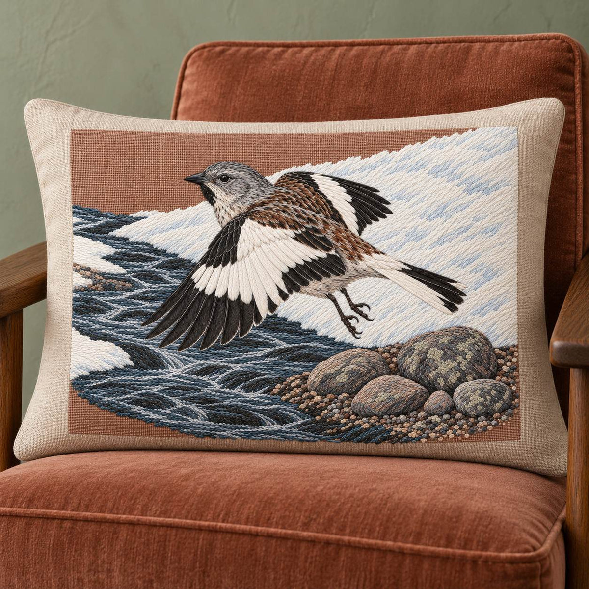 Snowfinch Along the Meltwater Cut visual mockup shown on a cushion in a lounge chair, with the design on warm oatmeal linen.