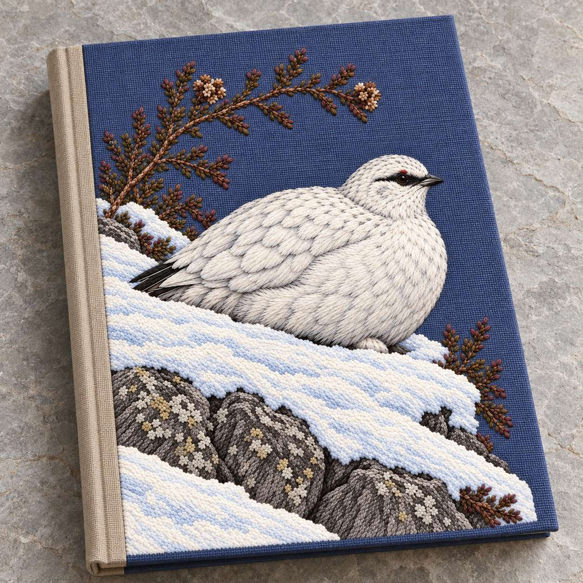 Ptarmigan Beneath the Wind Carved Heather visual mockup shown on a cloth portfolio cover, with the design on blue-violet linen.