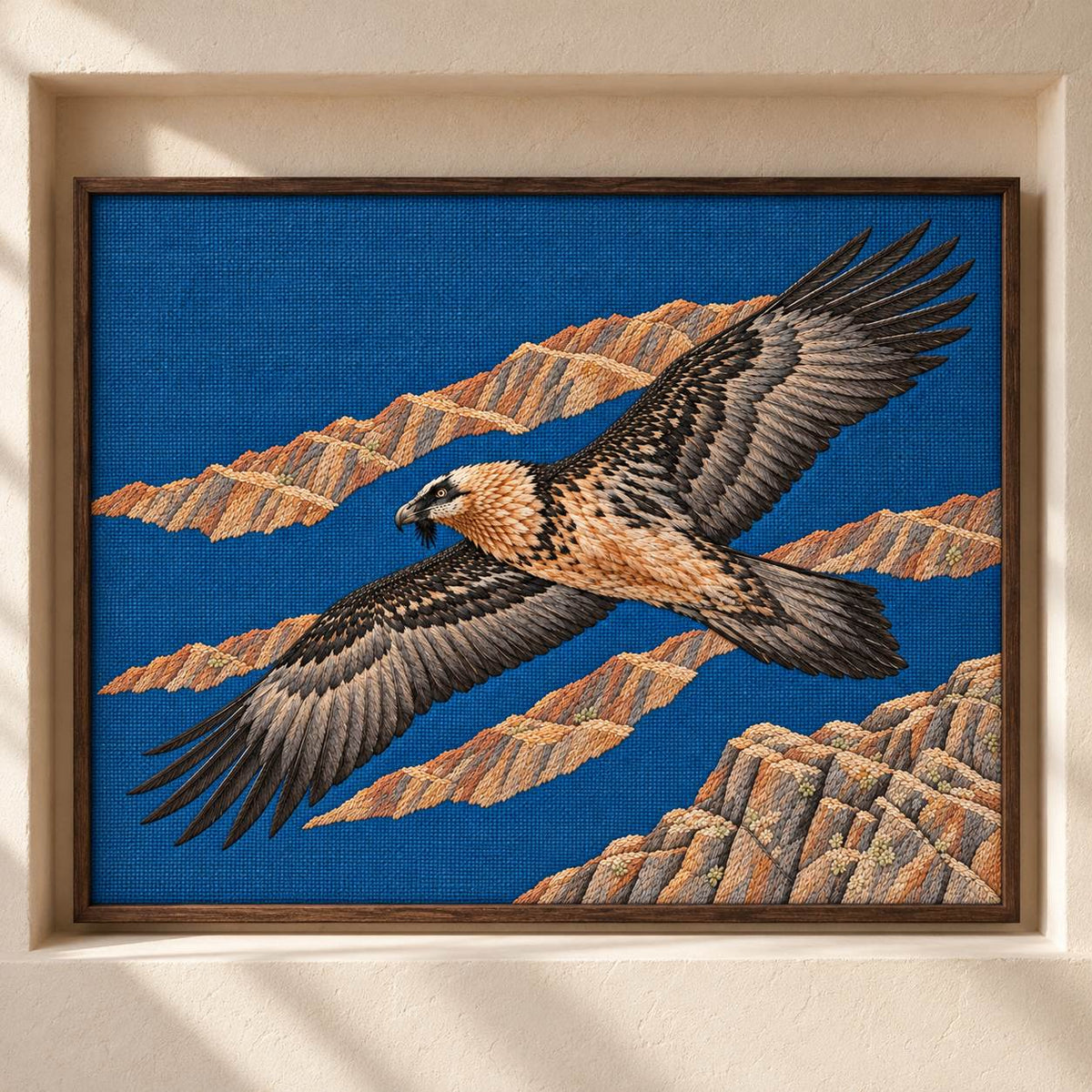 Lammergeier Through the Ochre Updraft visual mockup shown as a framed textile in a gallery niche, with the design on deep blue linen.