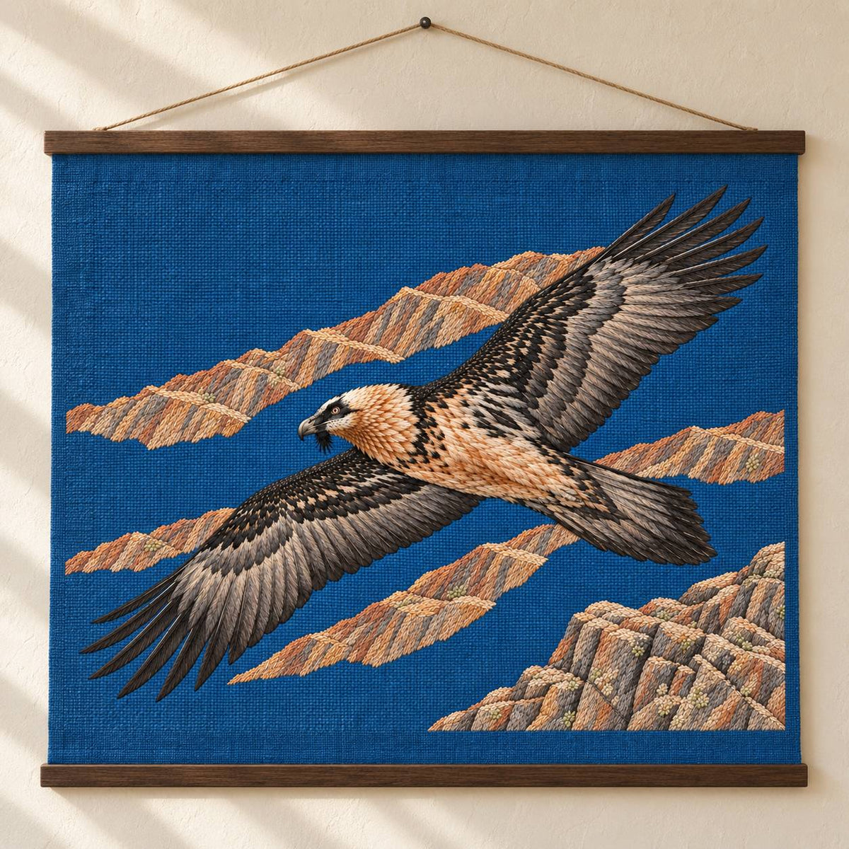 Lammergeier Through the Ochre Updraft visual mockup shown as a hanging textile held by wooden rails, with the design on deep blue linen.