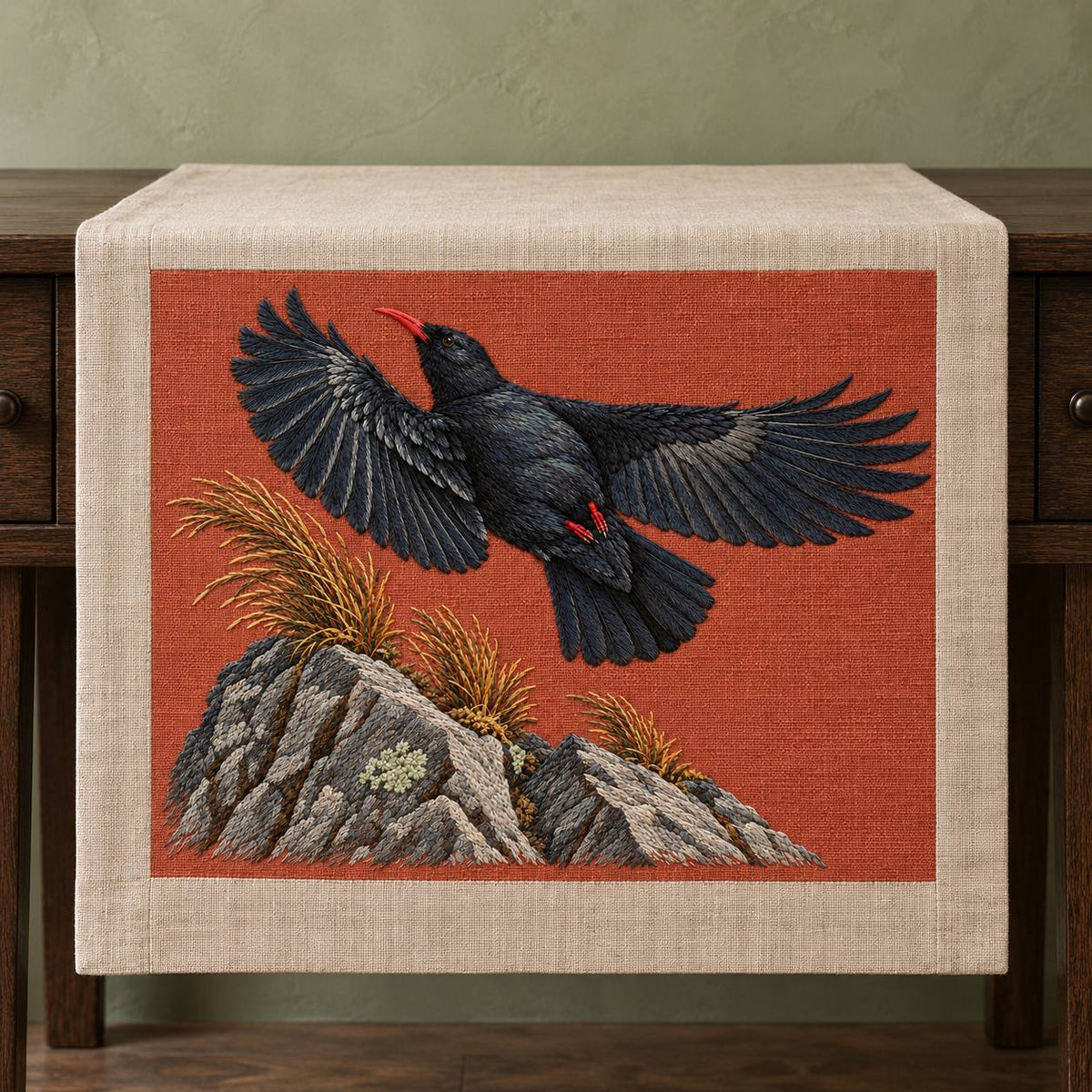 Chough at the Red Summit Flag visual mockup shown on a textile runner over a console, with the design on muted rust linen.