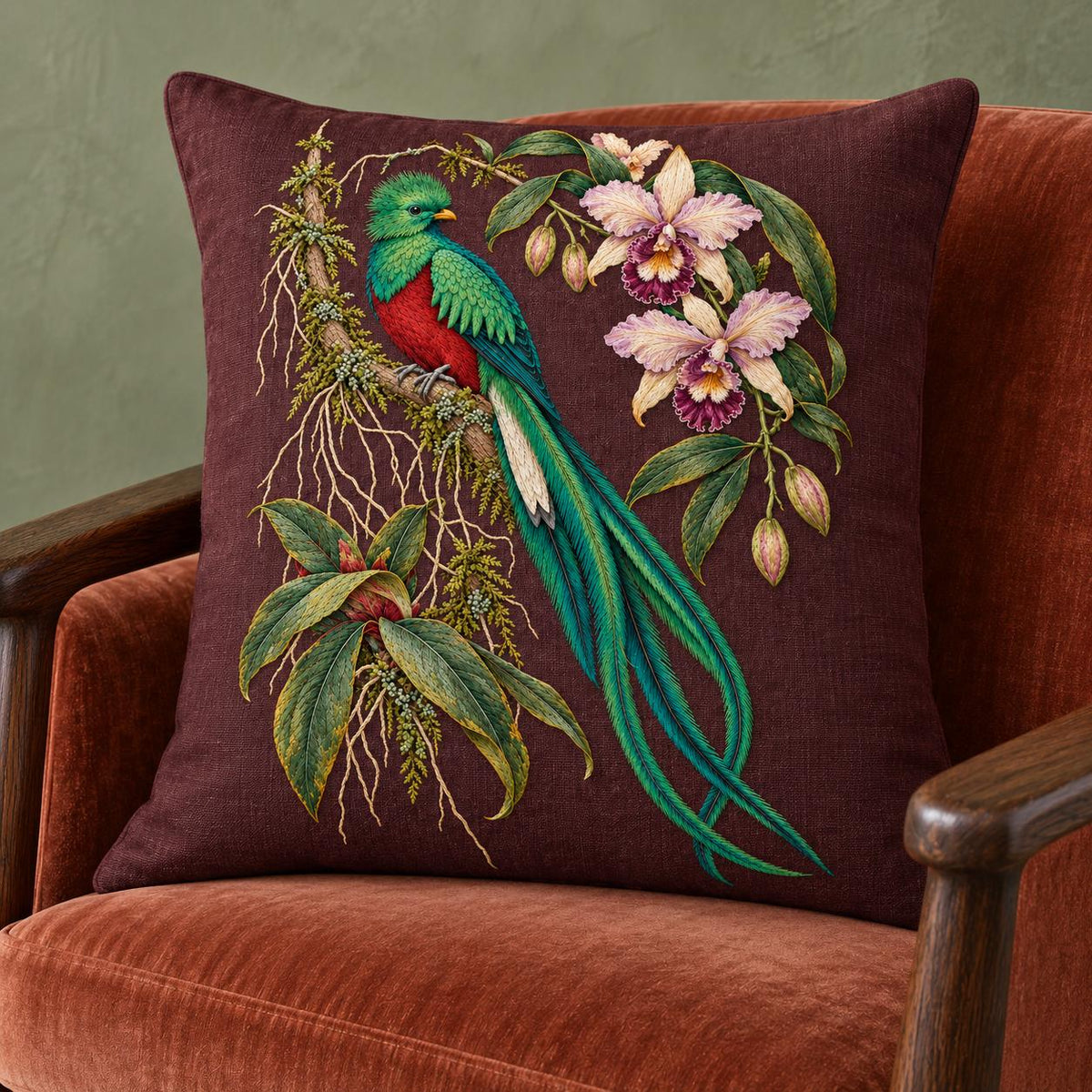 Quetzal Through the Orchid Arch visual mockup shown on a cushion in a lounge chair, with the design on deep burgundy-plum linen.
