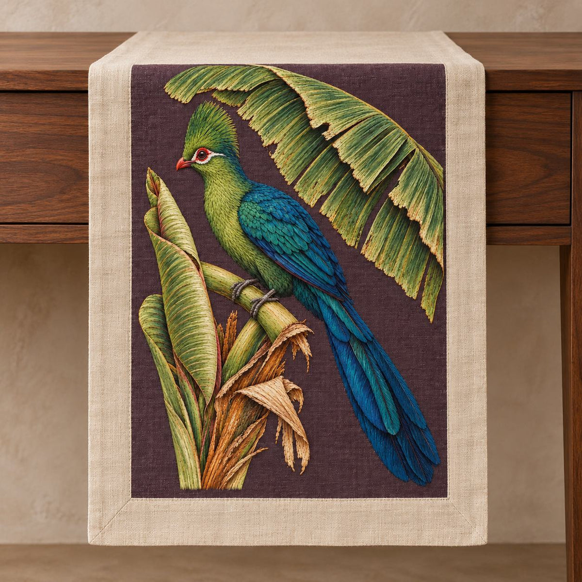 Turaco Beneath the Banana Rib Fan visual mockup shown on a textile runner over a console, with the design on deep plum linen.