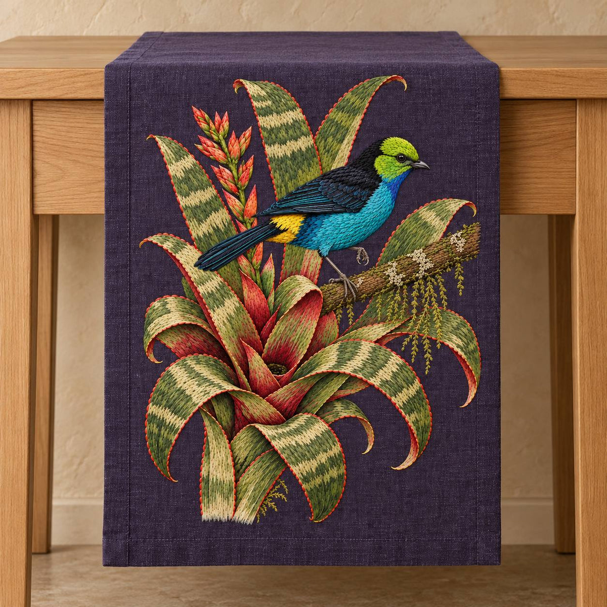Paradise Tanager in the Bromeliad Wheel visual mockup shown on a textile runner over a console, with the design on deep violet-slate linen.