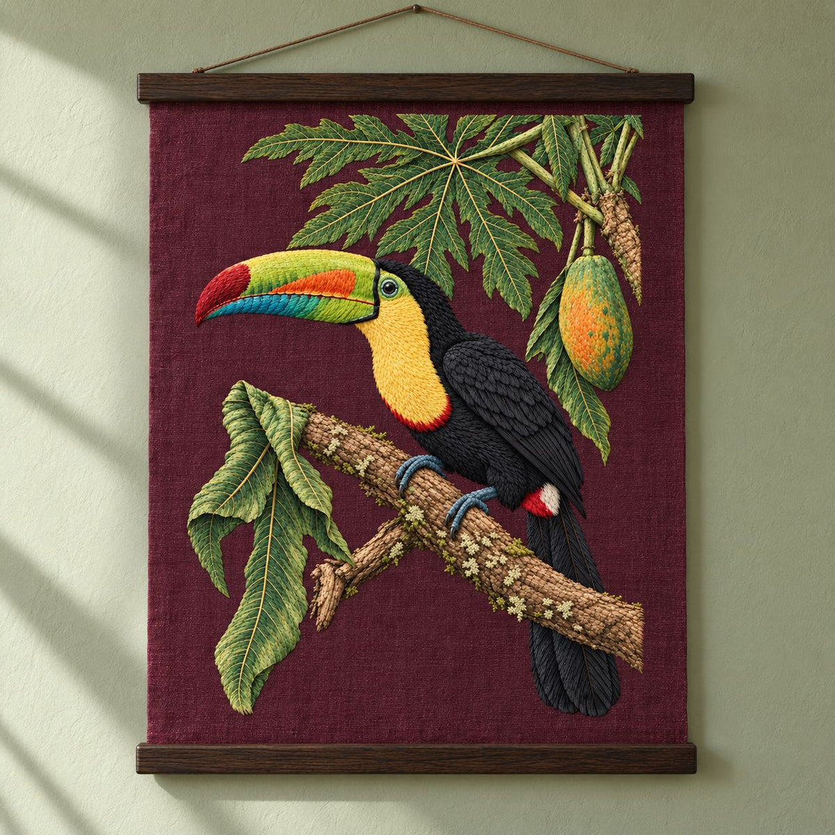 Toucan Under the Papaya Canopy visual mockup shown as a hanging textile held by wooden rails, with the design on deep burgundy linen.