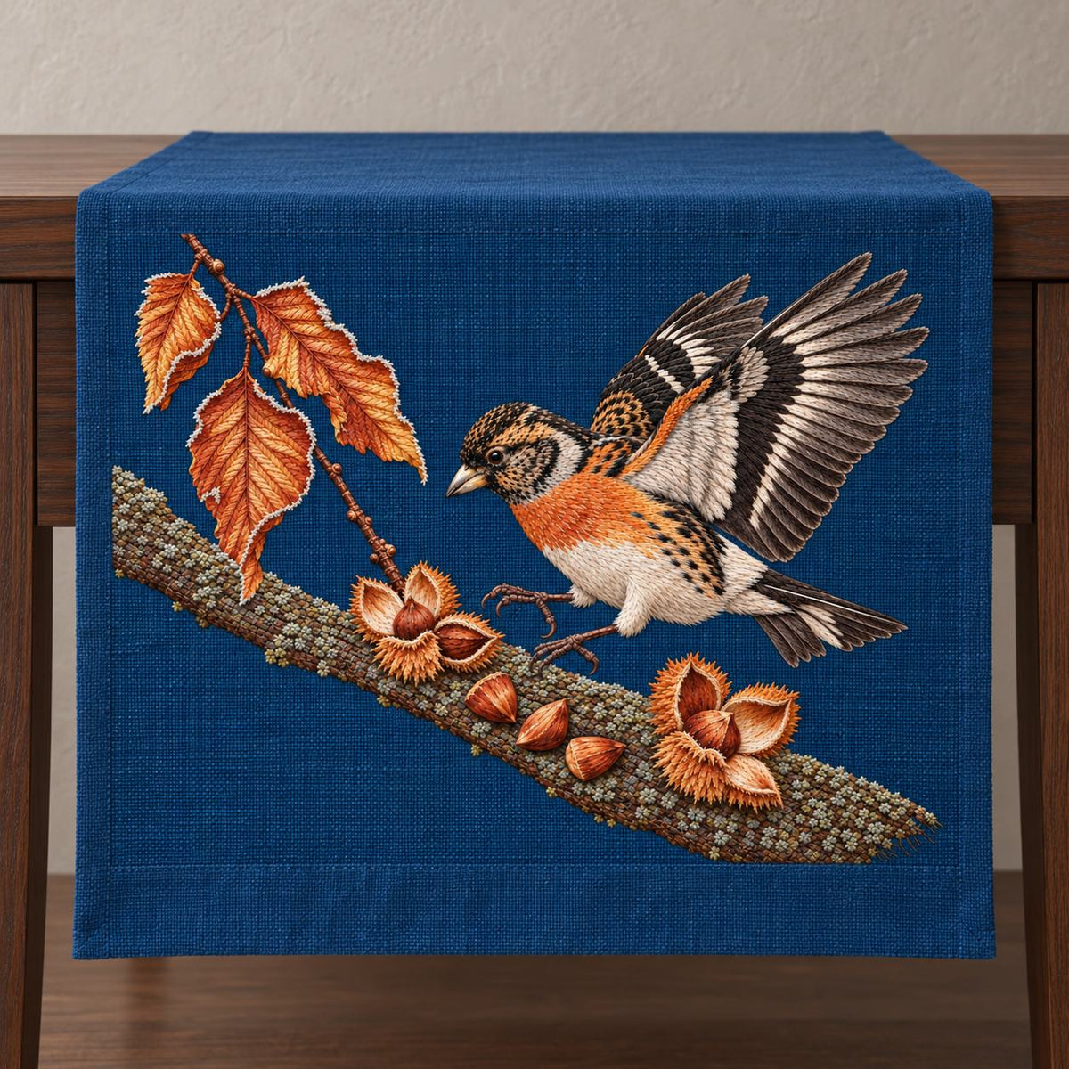 Brambling Above the Frosted Beech Mast visual mockup shown on a textile runner over a console, with the design on deep-blue linen.