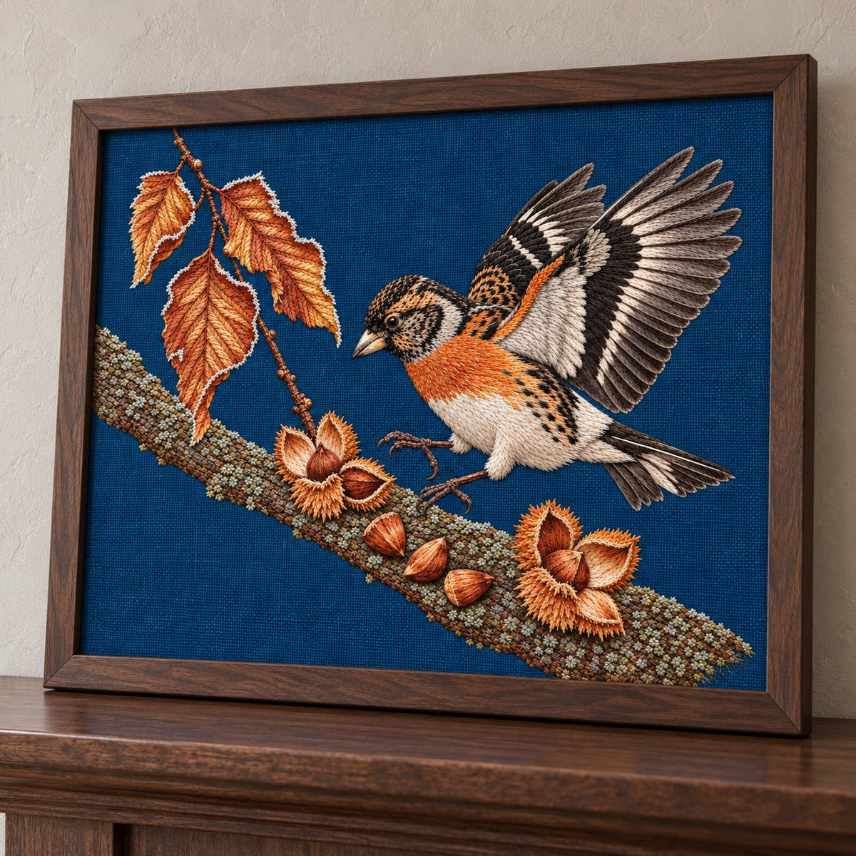 Brambling Above the Frosted Beech Mast visual mockup shown in a frame leaning on a mantel, with the design on deep-blue linen.