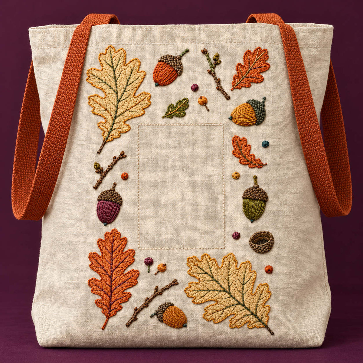 Linen tote bag mockup featuring the Acorn and Oak Fragment Grid hand embroidery design. Oak leaves, acorns and twig fragments sit around a tall clear rectangle.