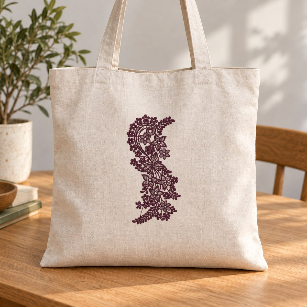 Ivory linen tote with a single aubergine paisley and wildflower vine embroidered vertically on the front.