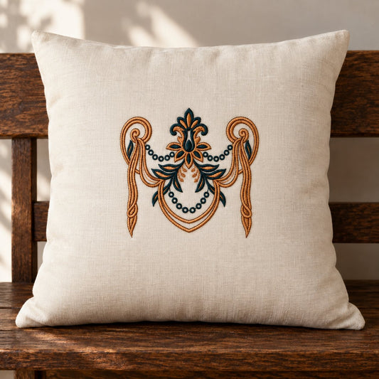 Copper and midnight teal baroque garland embroidered at the center of an ivory cushion on a dark wooden bench.