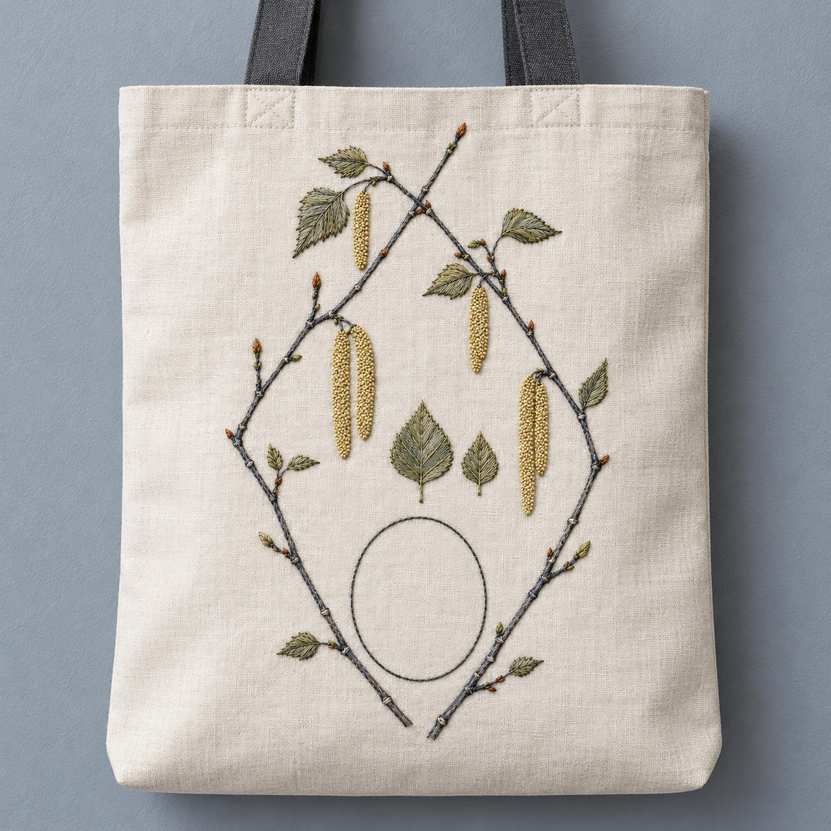 Linen tote bag mockup featuring the Birch Catkin Geometry hand embroidery design. Angular birch branches frame hanging catkins, central foliage and an unfilled oval.