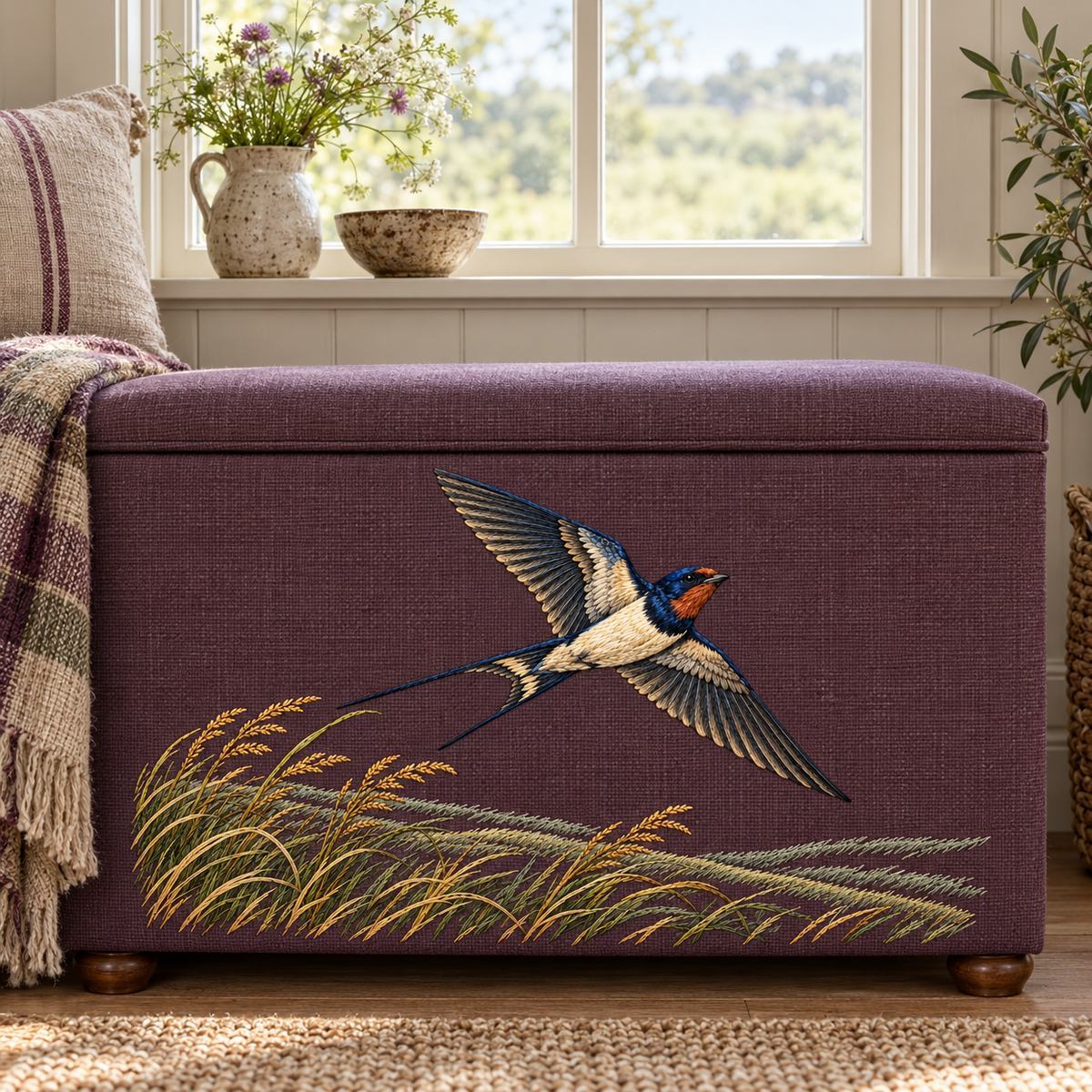 Swallow embroidery design in a digital mockup of wide plum linen storage bench front beneath a farmhouse window. Placement inspiration for Study 01.