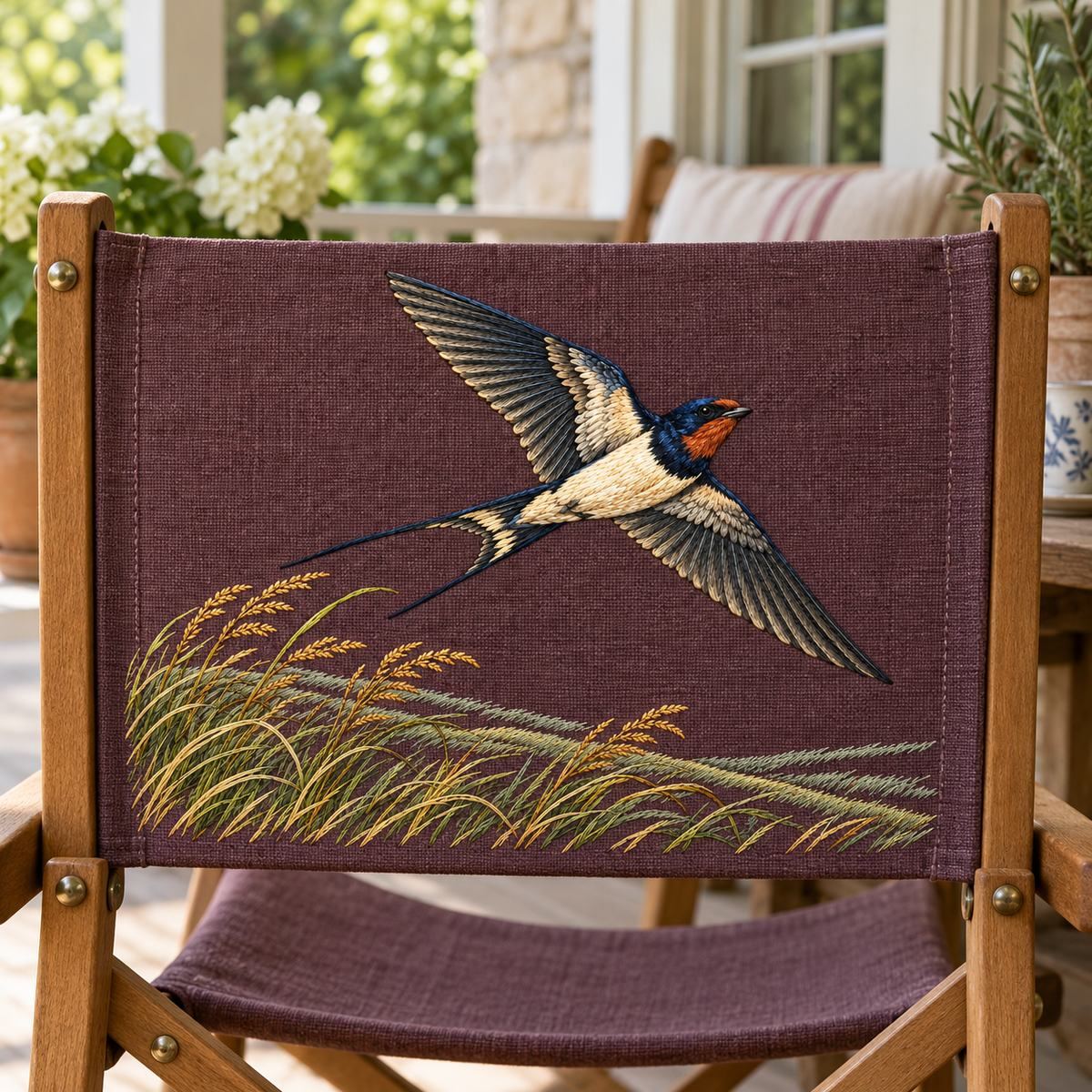 Swallow embroidery design in a digital mockup of rectangular embroidered panel on canvas folding camp stool back, cottage veranda. Placement inspiration for Study 01.