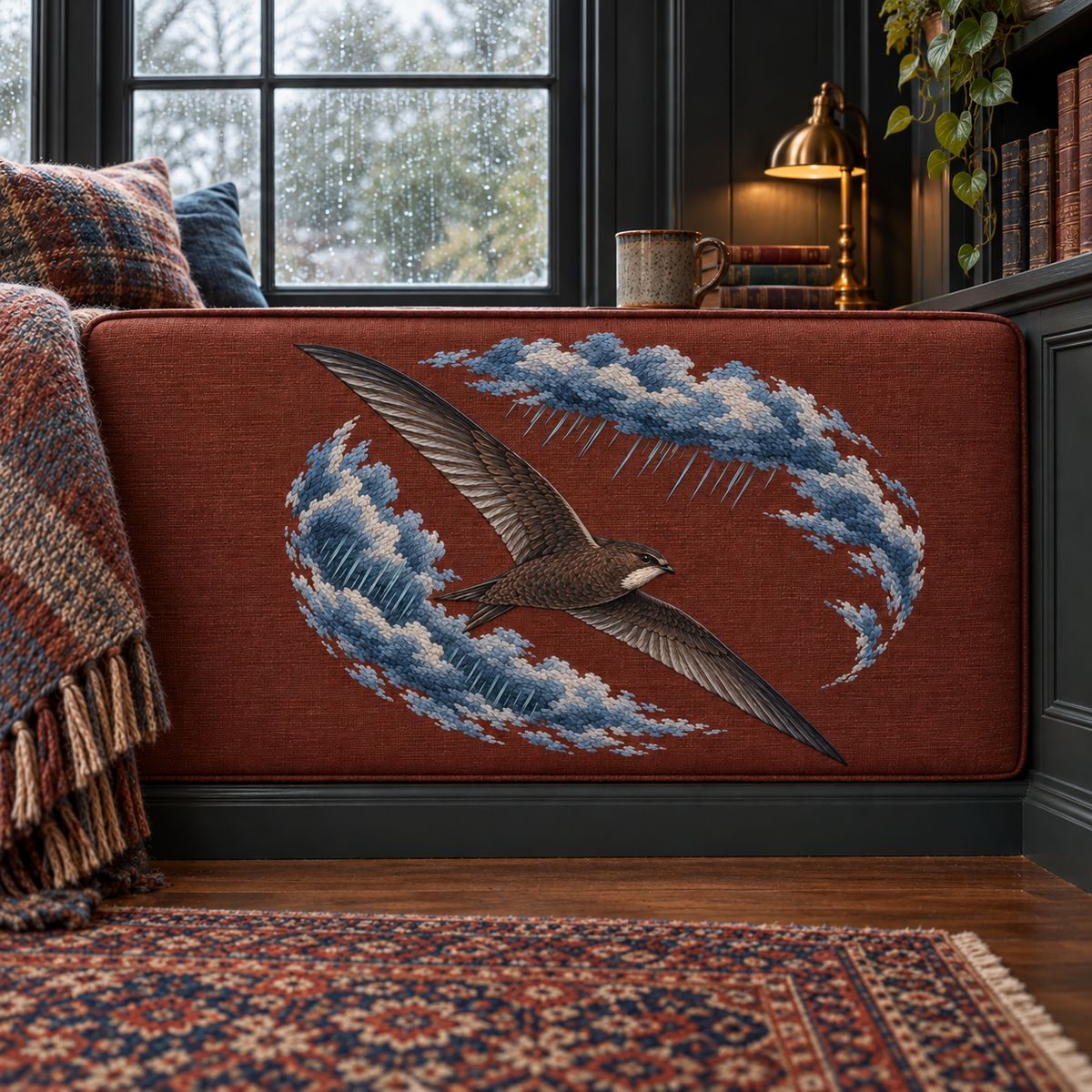 Swift embroidery design in a digital mockup of wide rectangular padded window-seat end panel in rainy library alcove. Placement inspiration for Study 02.