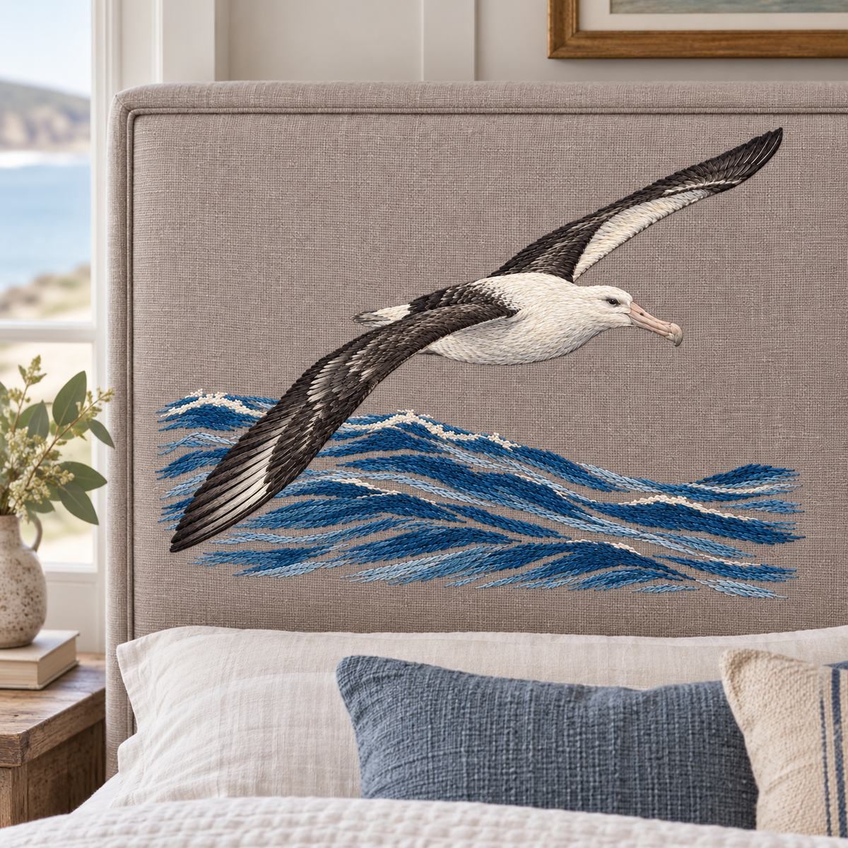 Albatross embroidery design in a digital mockup of landscape taupe linen padded headboard insert in a coastal guest room. Placement inspiration for Study 03.