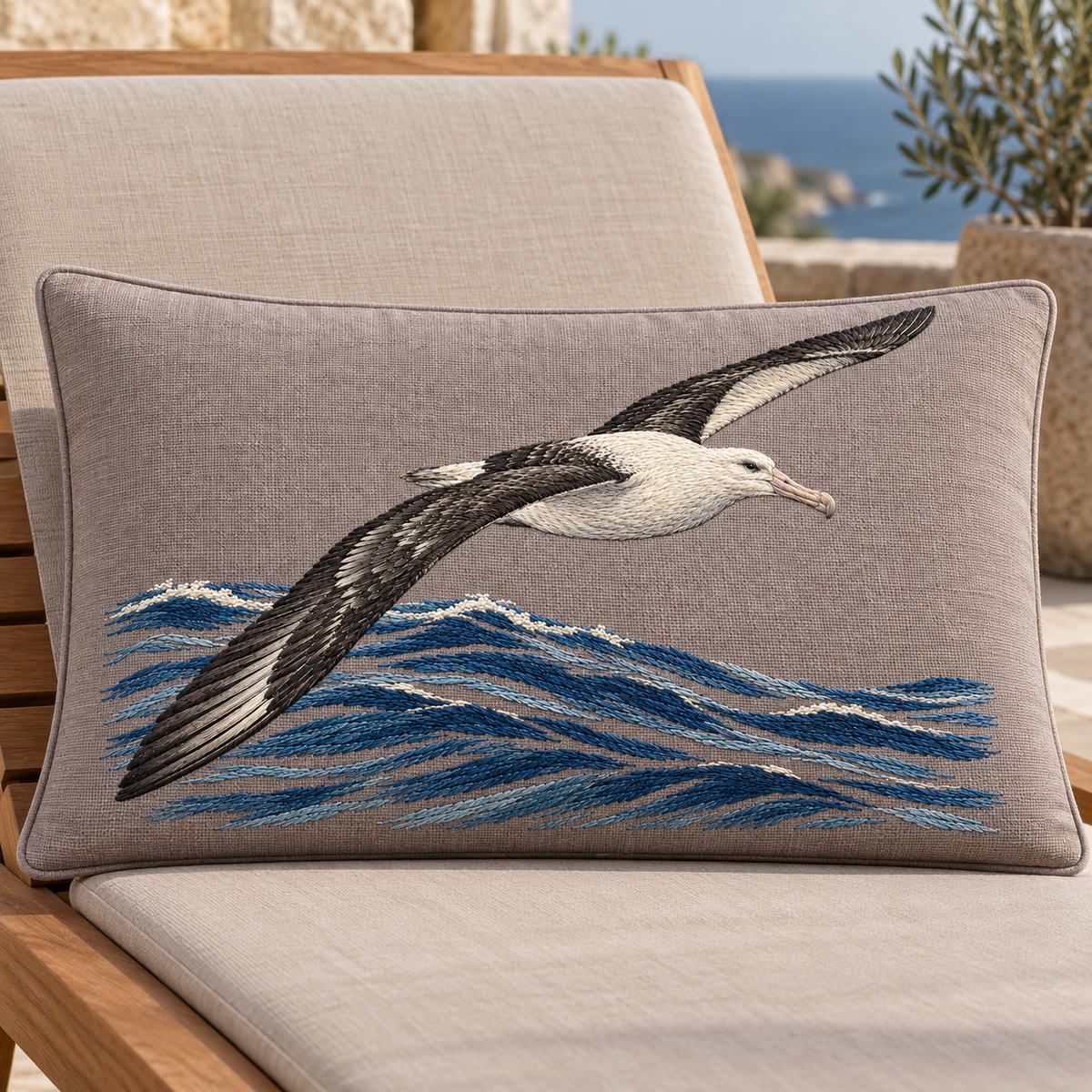 Albatross embroidery design in a digital mockup of wide rectangular taupe deck lounge headrest on wooden chaise. Placement inspiration for Study 03.