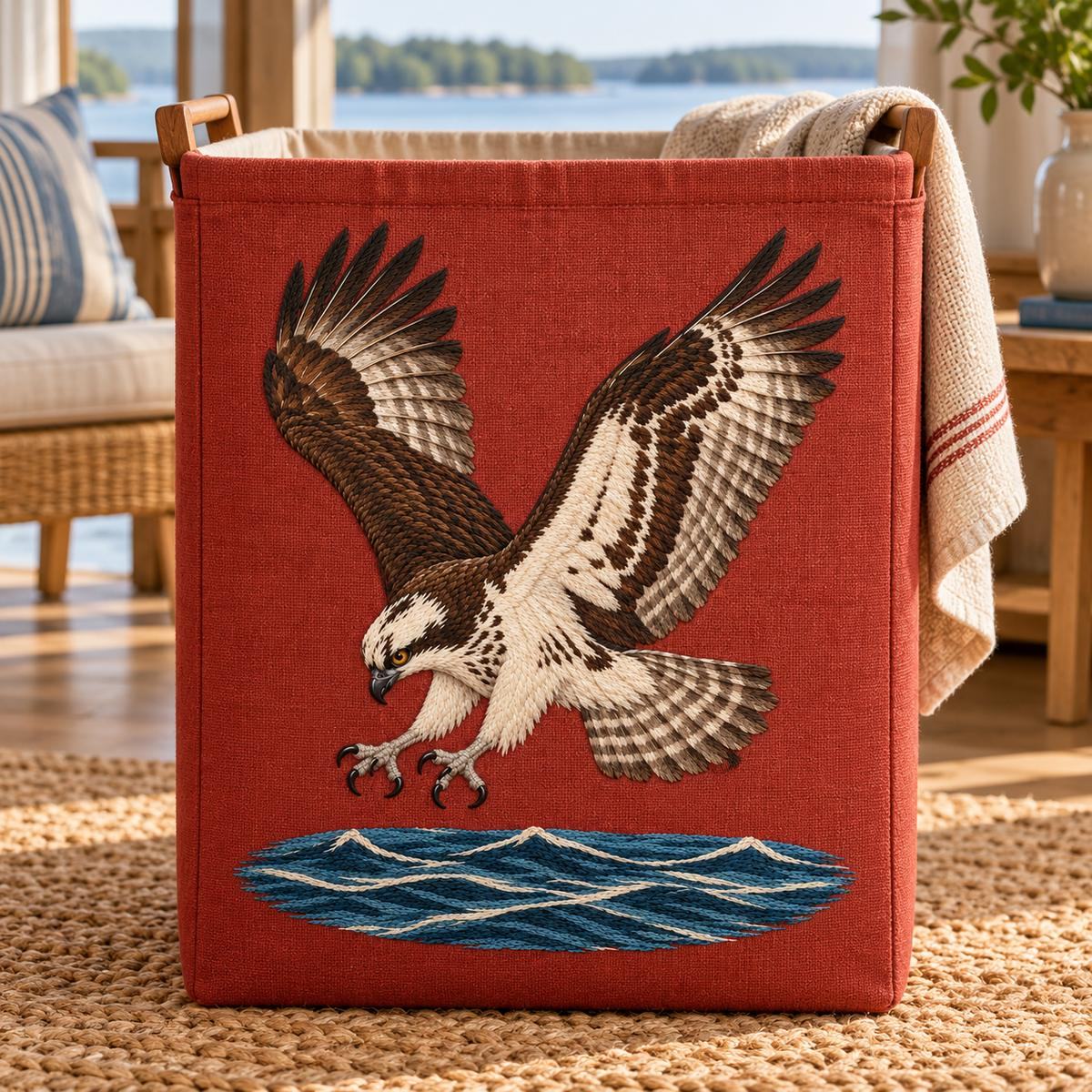 Osprey embroidery design in a digital mockup of A tall terracotta linen embroidered front on a rectangular laundry hamper in a calm lake-house room, water at bottom of panel. Placement inspiration for Study 09.