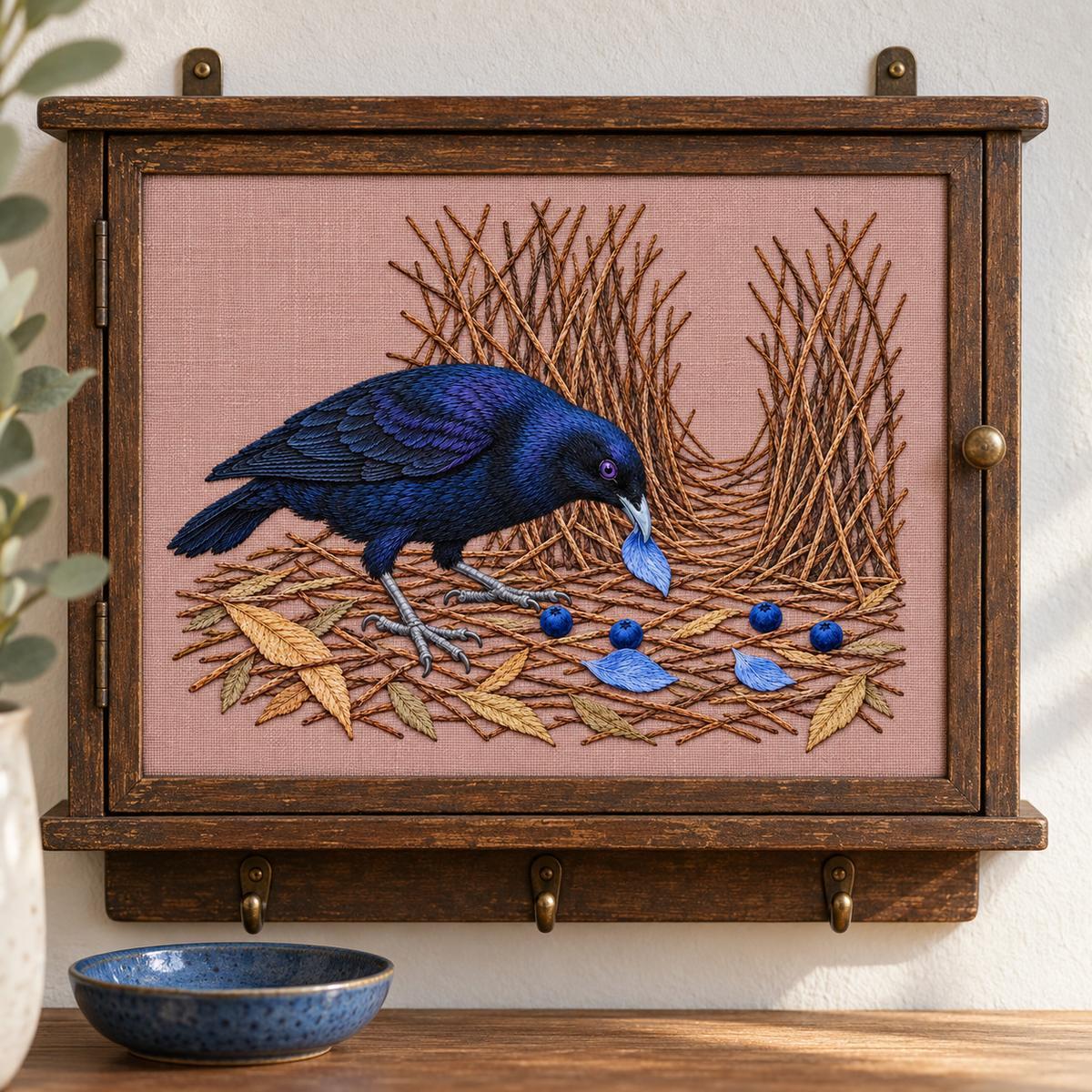 Satin Bowerbird hand embroidery design on a wooden hanging display. Digital placement mockup; finished item and materials are not included.