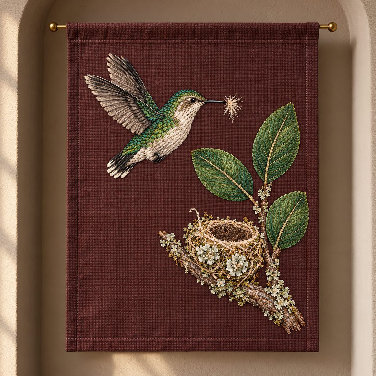 Bee Hummingbird embroidery design in a digital mockup of A portrait soft textile art banner hanging from a single slim brass rod, plain mulberry background, side light in a narrow alcove, full nest and bird visible. Placement inspiration for Study 29.