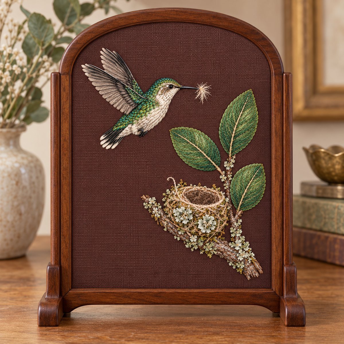 Bee Hummingbird embroidery design in a digital mockup of A mulberry linen panel in a delicate oval-topped rectangular wood screen for a tabletop, entire 232x300mm rectangular motif visible inside the frame, close frontal photograph. Placement inspiration for Study 29.